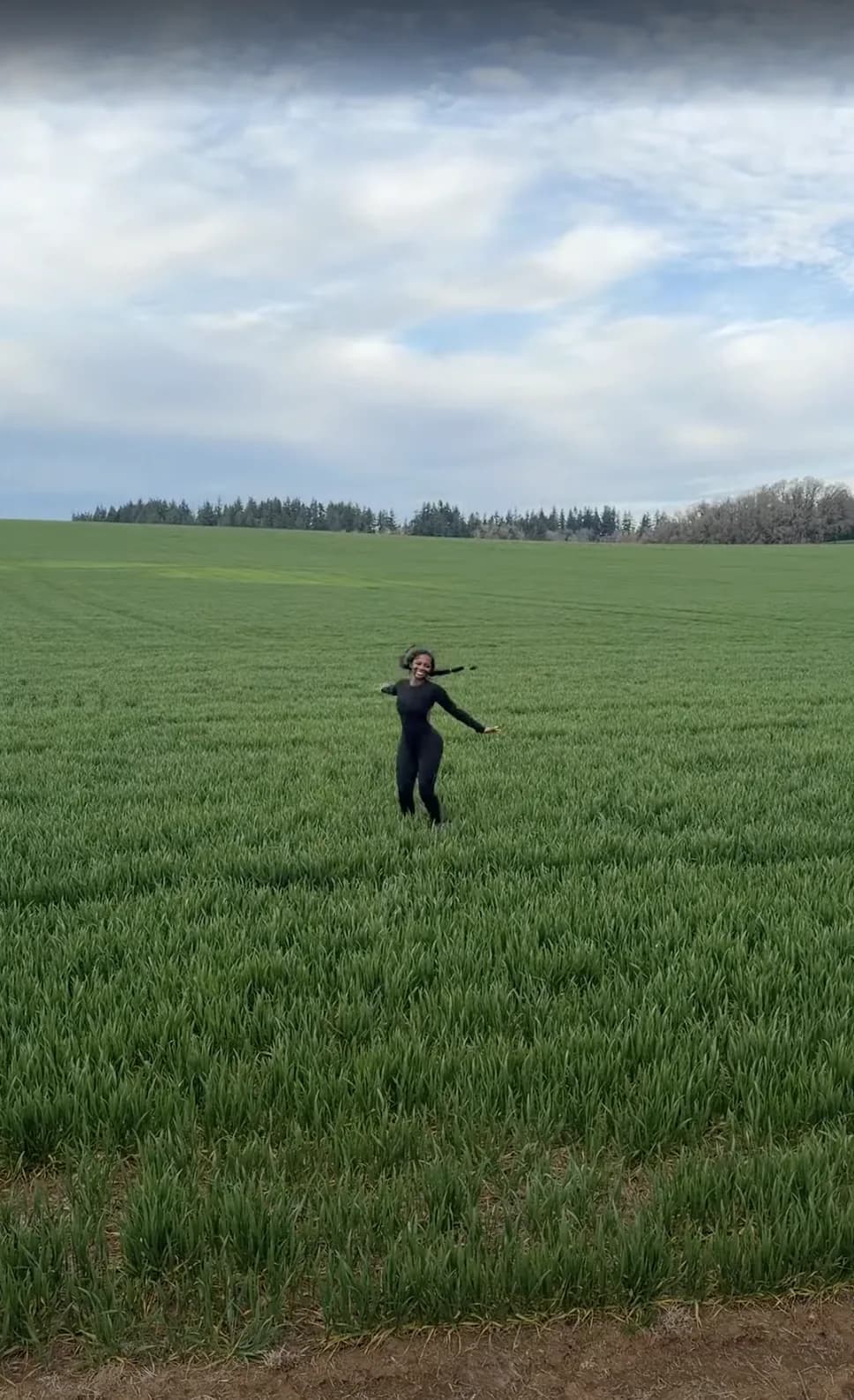 Ashly joyously running through a green field on the side of the road, the day after the events in Bend.